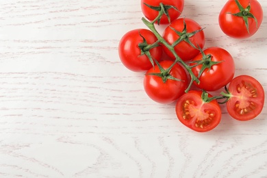 Photo of Fresh cherry tomatoes on white wooden background, top view. Space for text