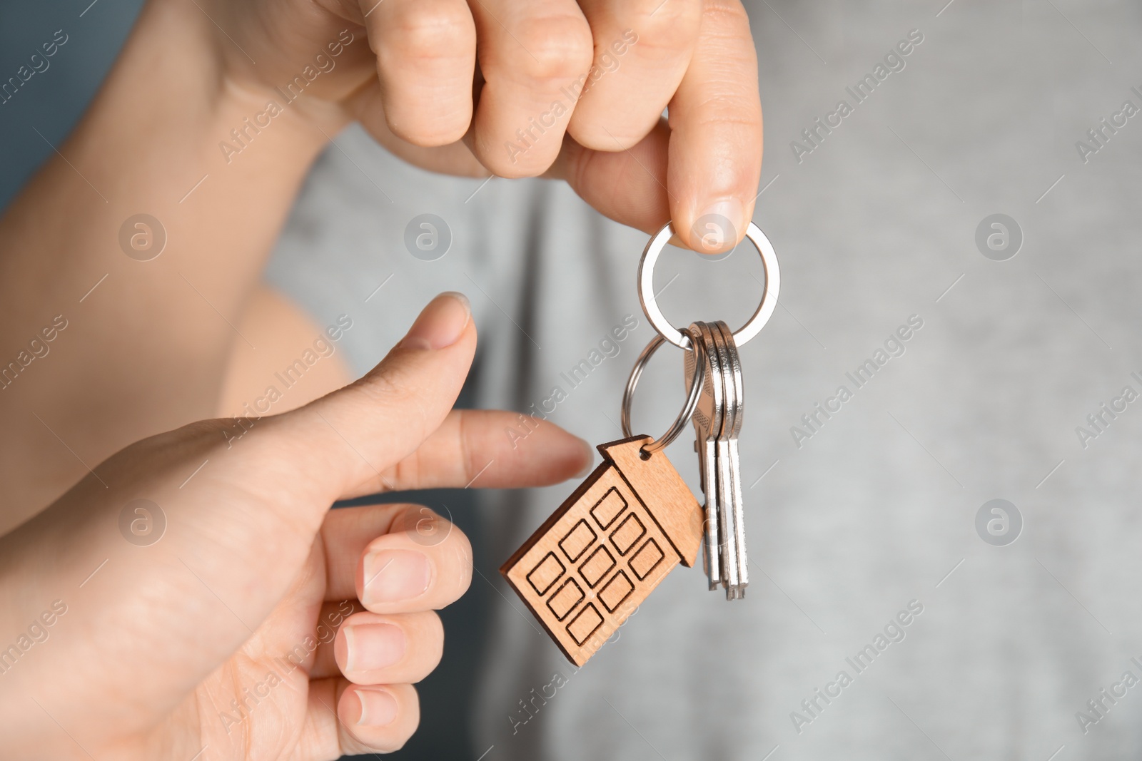 Photo of Man giving house key with trinket to woman, closeup