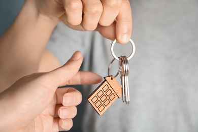 Photo of Man giving house key with trinket to woman, closeup