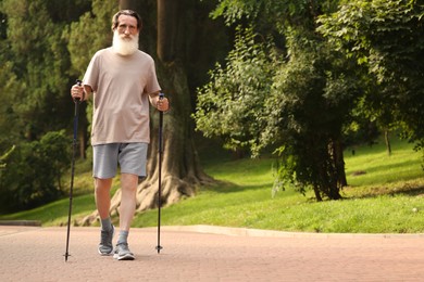 Photo of Senior man performing Nordic walking outdoors, space for text. Low angle view