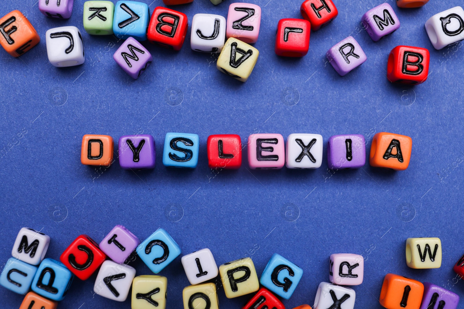 Photo of Colorful beads with word Dyslexia on blue background, flat lay