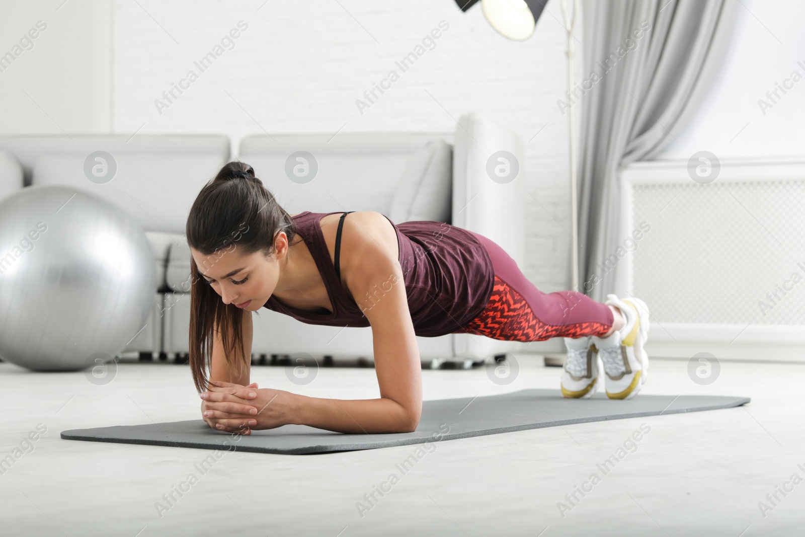 Photo of Young woman in fitness clothes doing exercise at home
