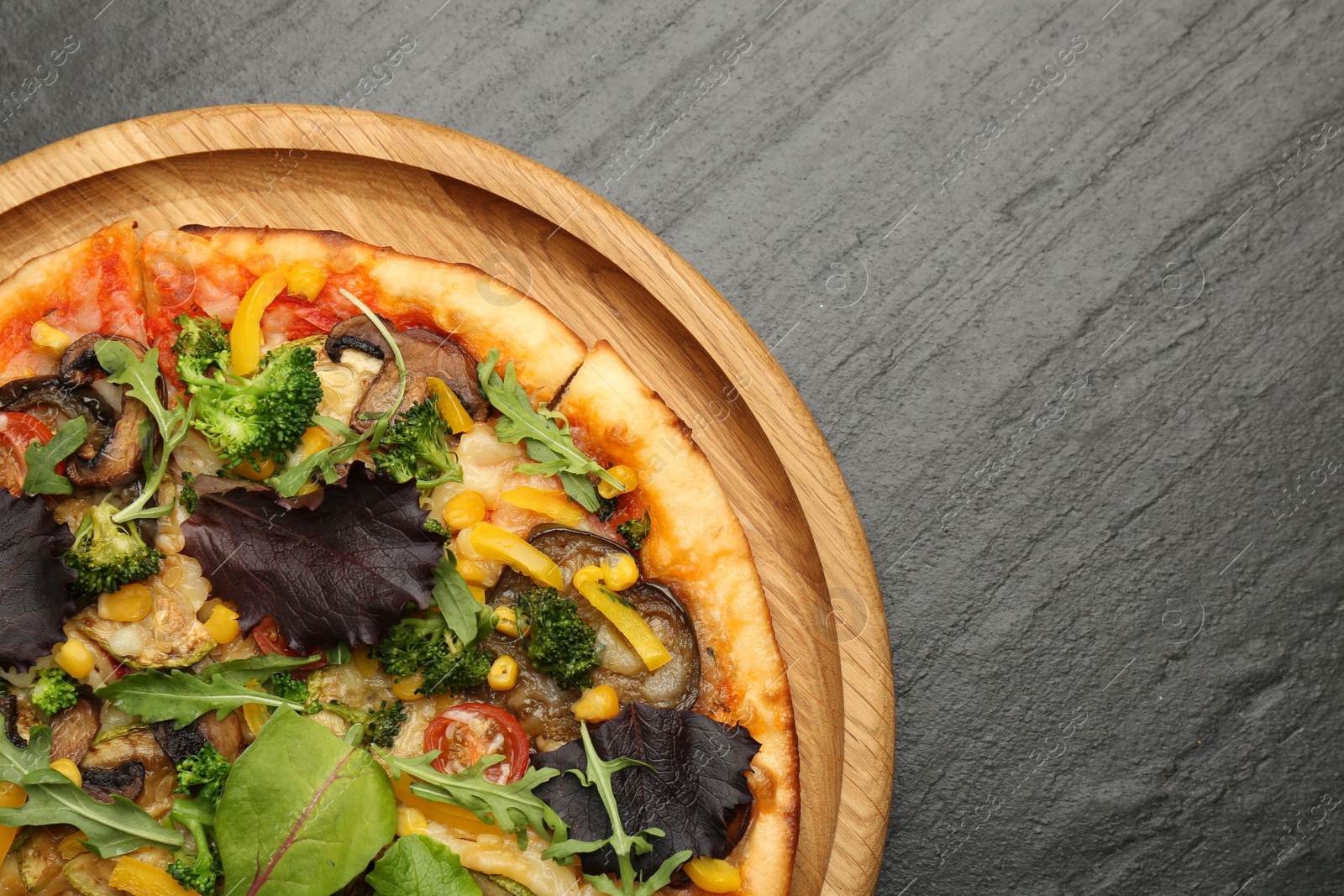 Photo of Delicious vegetarian pizza with mushrooms, vegetables and greens on black table, top view. Space for text