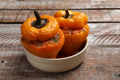 Photo of Tasty stuffed peppers in bowl on wooden rustic table, closeup