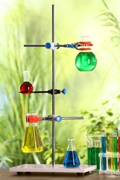 Photo of Laboratory glassware with colorful liquids on table against blurred background