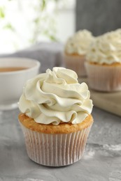 Photo of Tasty cupcake with vanilla cream on grey table, closeup