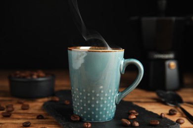 Photo of Cup of tasty coffee and beans on wooden table