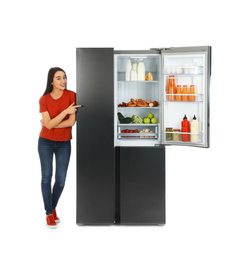 Photo of Young woman near open refrigerator on white background