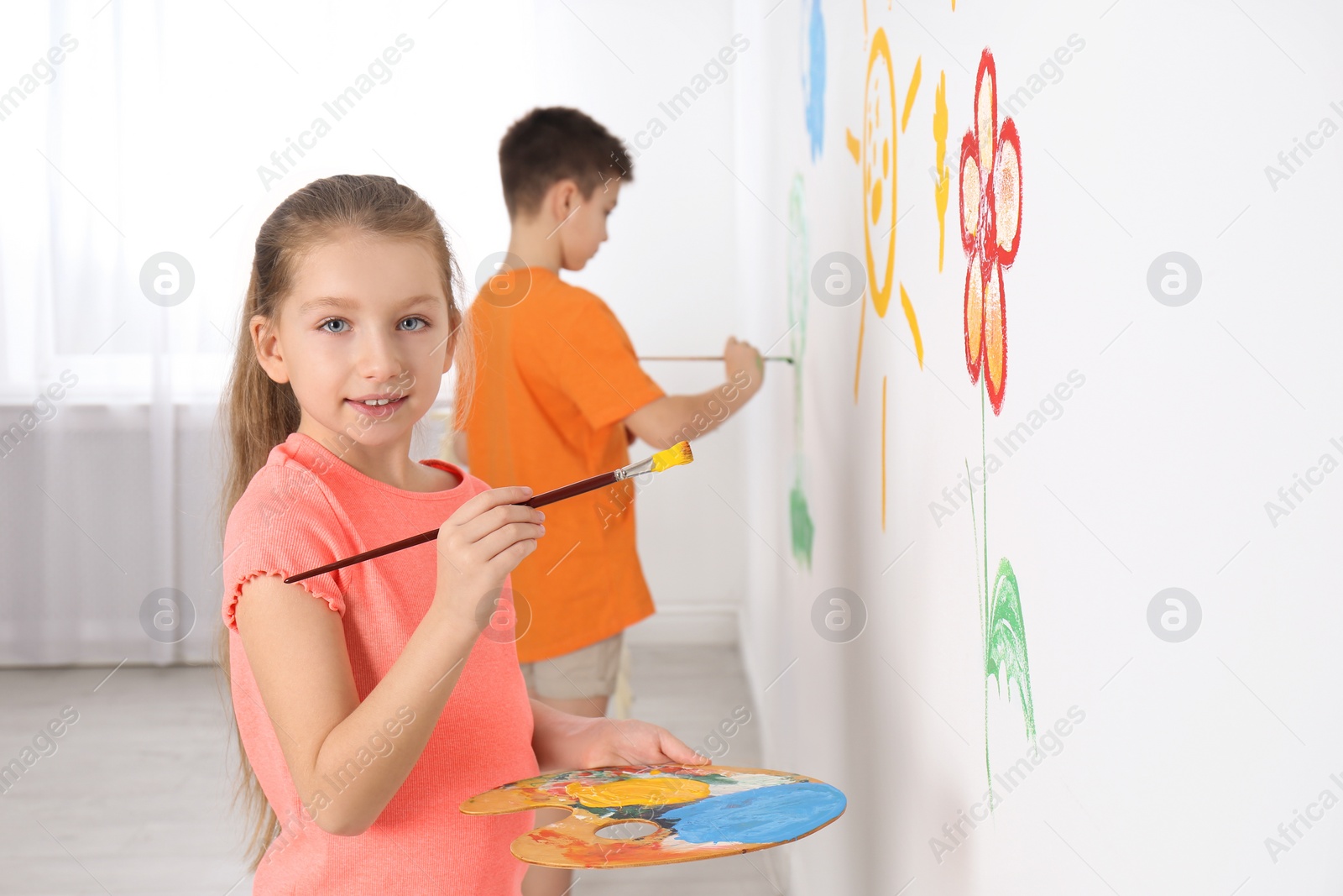 Photo of Little children painting on white wall indoors