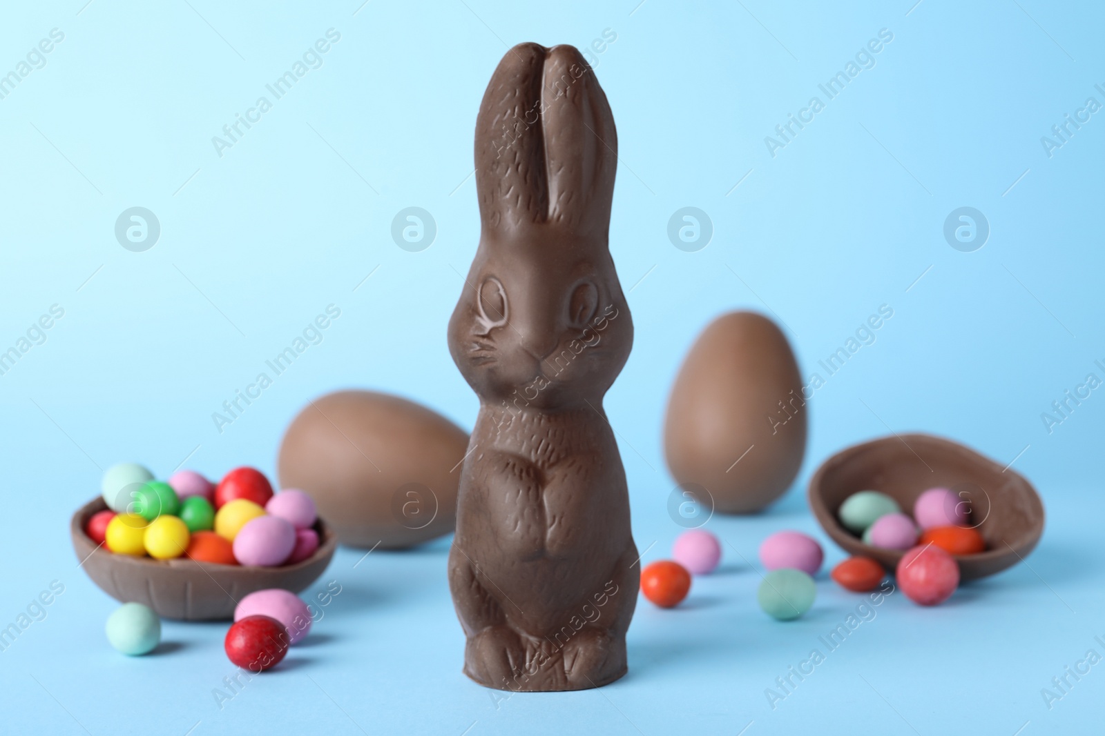 Photo of Chocolate Easter bunny and eggs on light blue background