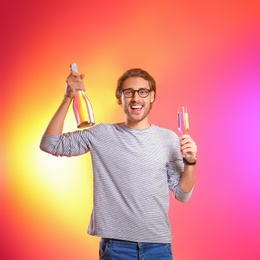 Photo of Portrait of happy man holding bottle and glass with champagne on color background