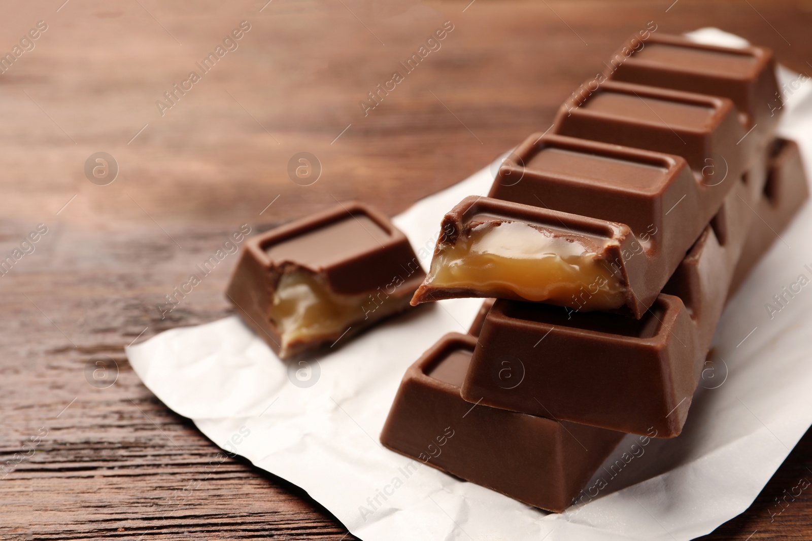 Photo of Tasty chocolate bars on wooden table, closeup. Space for text
