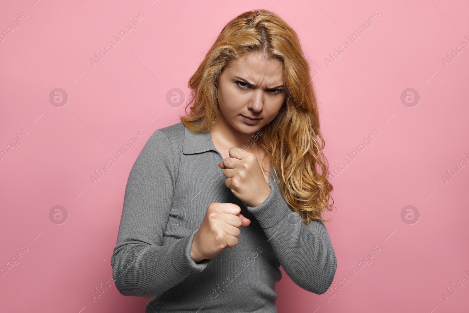 Photo of Angry young woman ready to fight on pink background