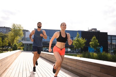 Healthy lifestyle. Happy couple running outdoors on sunny day, low angle view