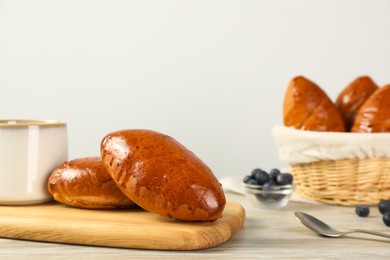 Photo of Delicious baked pirozhki on wooden table, space for text