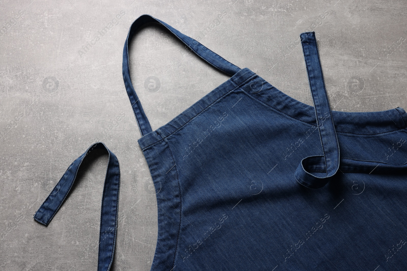 Photo of Stylish blue apron on grey table, top view. Mockup for design