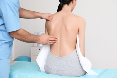 Photo of Orthopedist examining woman's back in clinic, closeup. Scoliosis treatment