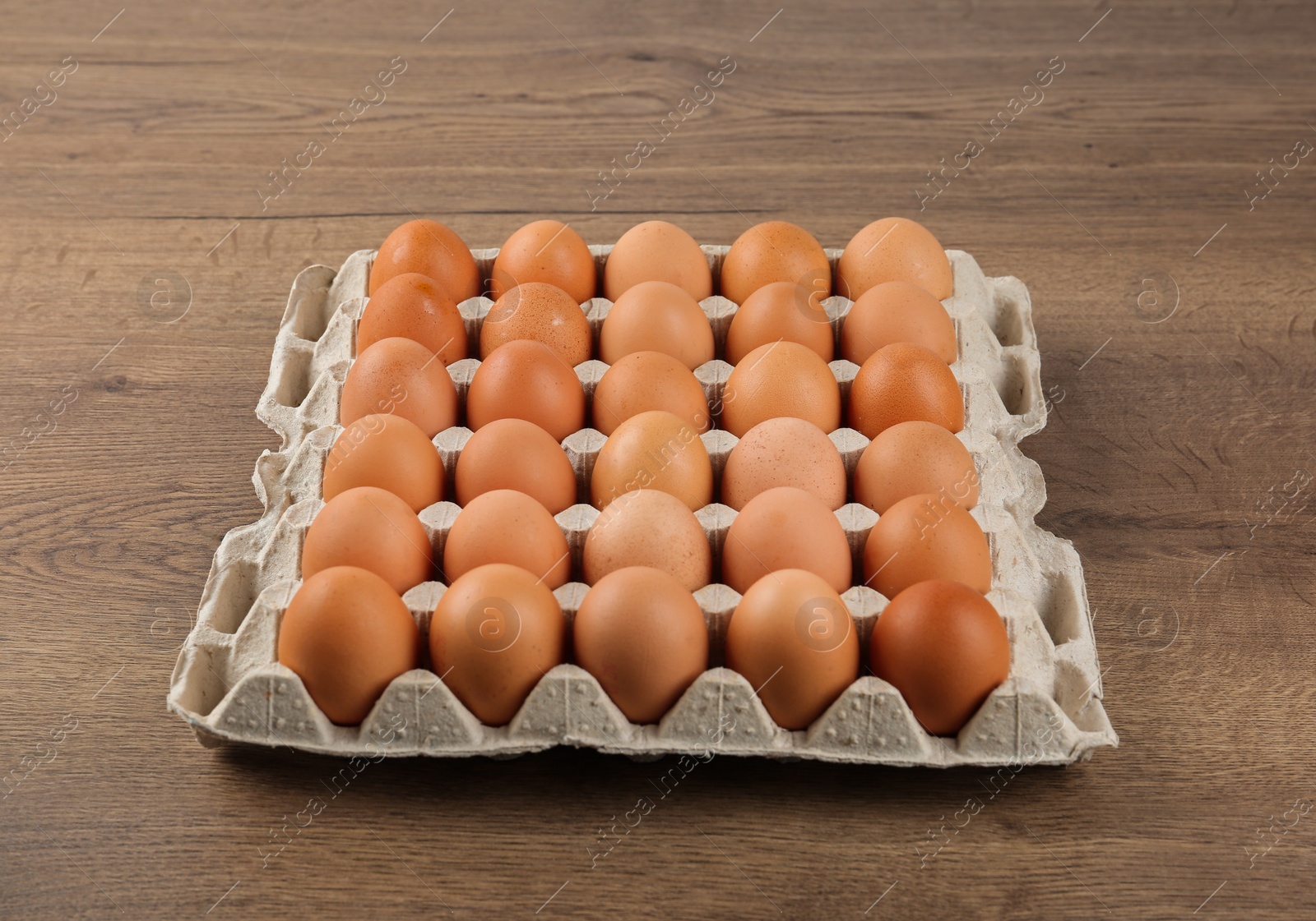 Photo of Raw chicken eggs in carton tray on wooden table