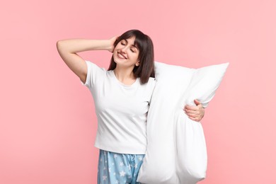 Photo of Happy woman in pyjama holding pillow on pink background