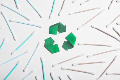 Photo of Recycling symbol, plastic and wooden cotton swabs on white background, top view