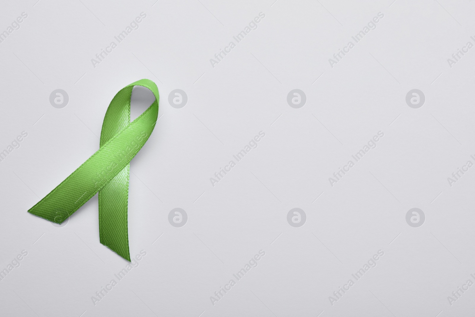 Photo of World Mental Health Day. Green ribbon on white background, top view with space for text