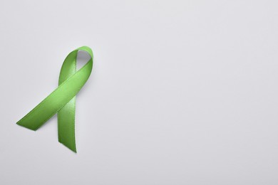 Photo of World Mental Health Day. Green ribbon on white background, top view with space for text
