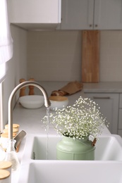 Photo of Bouquet of gypsophila flowers in sink. Kitchen interior design