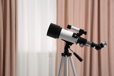 Photo of Tripod with modern telescope in stylish room, closeup. Space for text