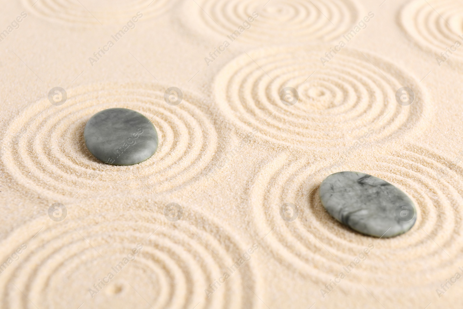 Photo of Zen garden stones on beige sand with pattern