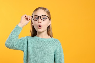 Photo of Portrait of emotional girl in glasses on orange background. Space for text