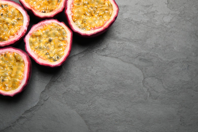 Photo of Halves of passion fruits (maracuyas) on black slate table, flat lay. Space for text