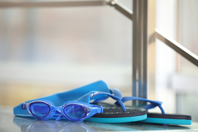 Photo of Swimming cap, goggles and flip flops against blurred background. Space for text