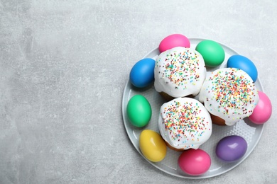 Photo of Easter cakes and colorful eggs on light grey table, top view