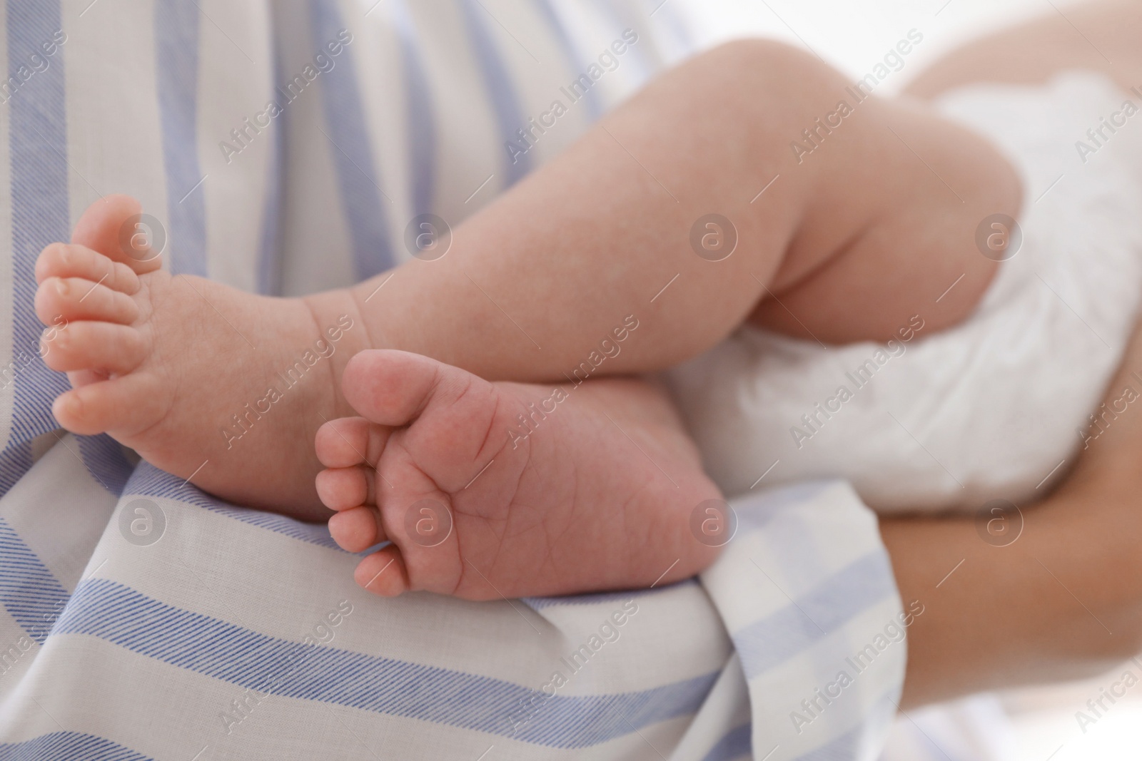 Photo of Mother holding her cute child in diaper at home, closeup