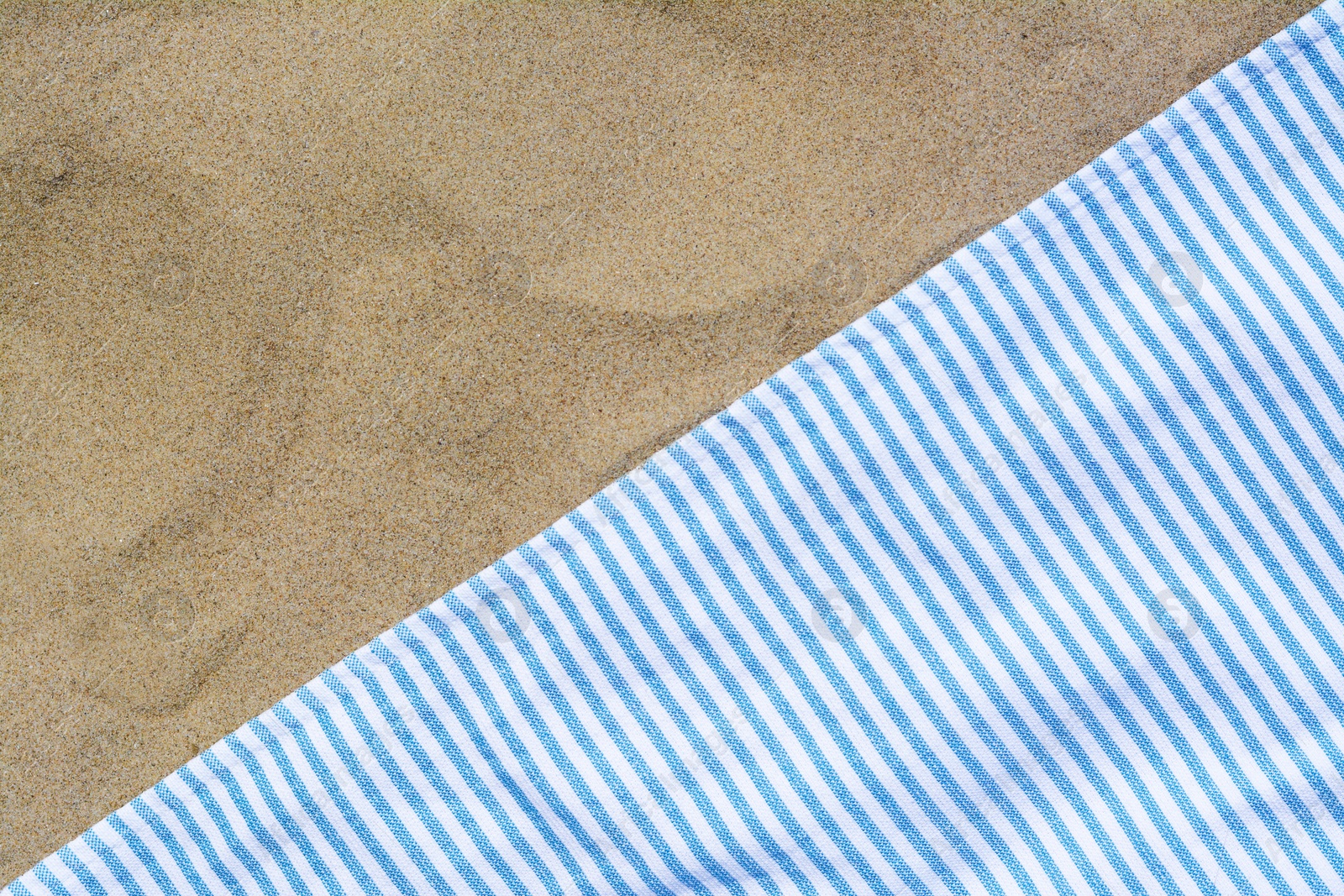 Photo of White and light blue striped towel on sandy beach, top view. Space for text