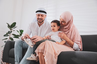 Happy Muslim family spending time together on sofa at home