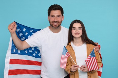 Photo of 4th of July - Independence Day of USA. Happy man and his daughter with American flags on light blue background