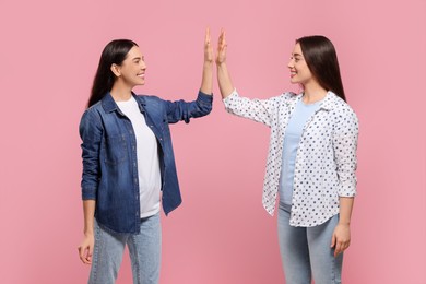 Women giving high five on pink background