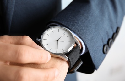 Businessman winding up his wrist watch, closeup. Time management