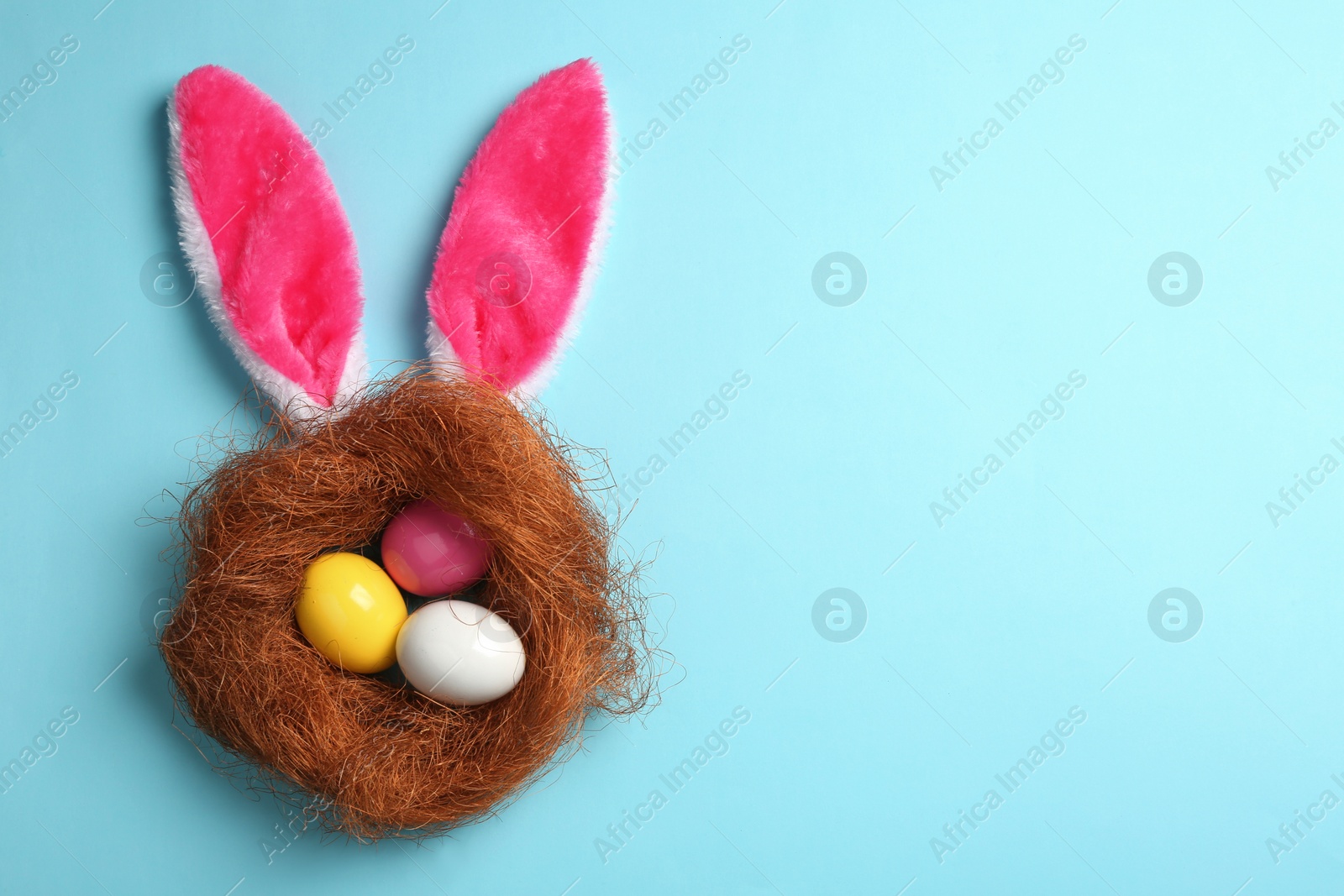 Photo of Flat lay composition of Easter bunny ears with eggs on color background, space for text