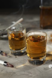 Photo of Alcohol and drug addiction. Whiskey in glasses and syringes on grey background