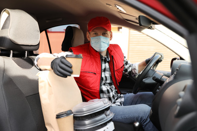 Photo of Courier in protective mask and gloves with orders inside car. Food delivery service during coronavirus quarantine