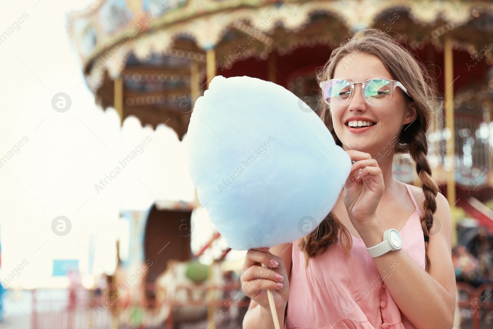 Photo of Young woman with cotton candy in amusement park. Space for text