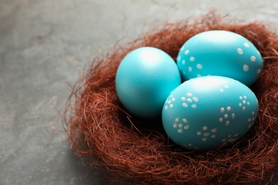 Photo of Sisal nest with painted Easter eggs on color background, closeup. Space for text