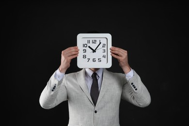 Photo of Businessman holding clock on black background. Time management