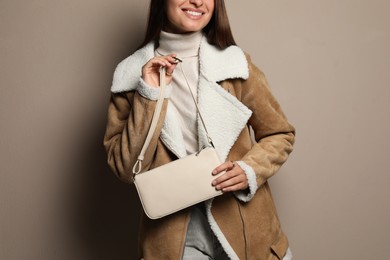 Photo of Fashionable young woman with stylish bag on beige background, closeup