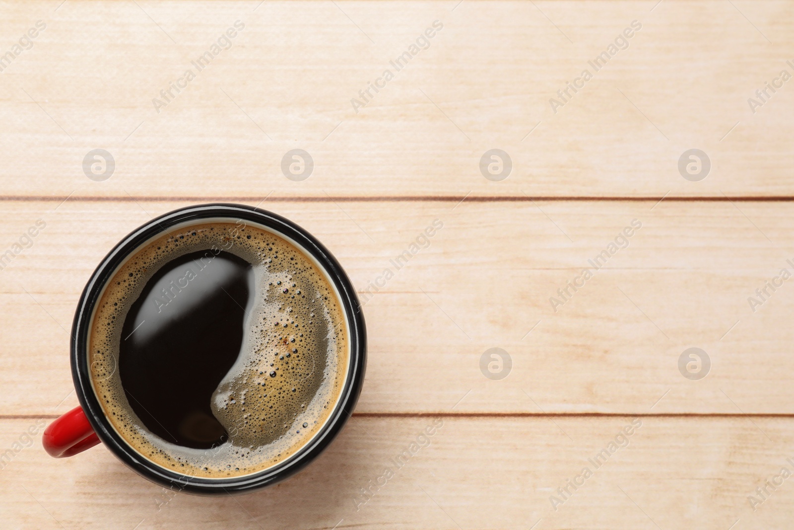 Photo of Cup of aromatic coffee on light wooden table, top view. Space for text