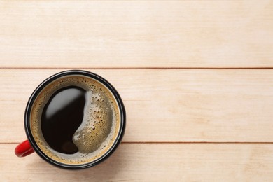 Cup of aromatic coffee on light wooden table, top view. Space for text