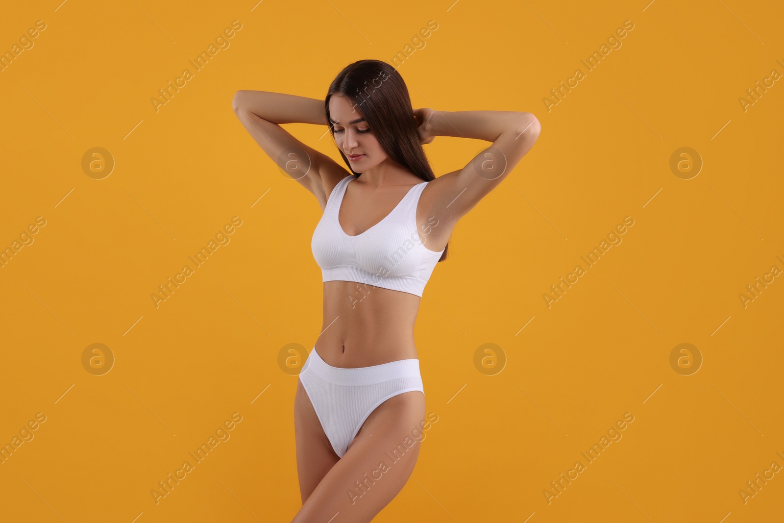 Photo of Young woman in stylish white bikini on orange background