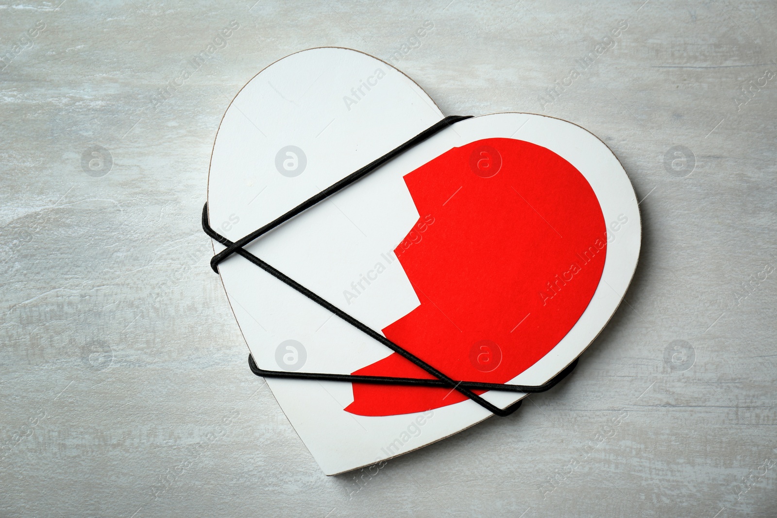 Photo of Half of cut paper heart tied with cord to detail on gray background, top view. Relationship problems